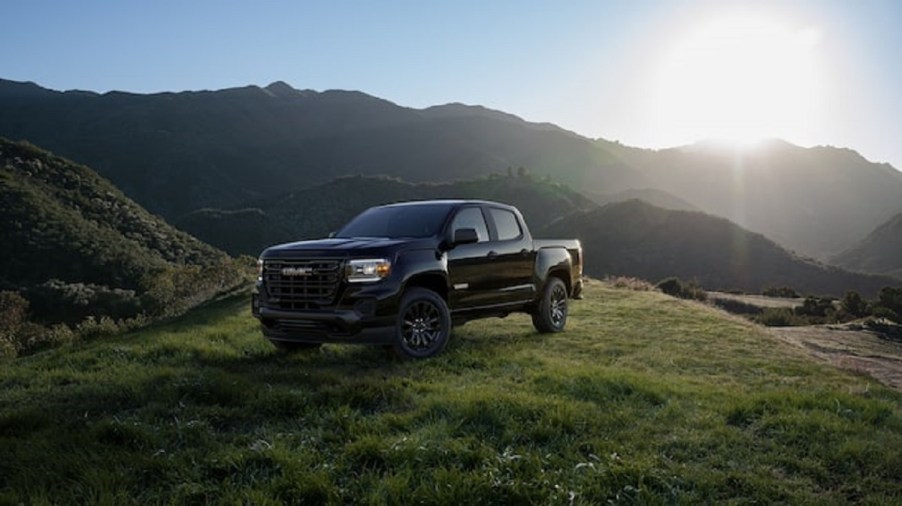 A black 2020 GMC Canyon sits atop a grassy hill.