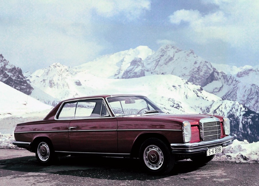 A red 1967 Mercedes 'W114' 250C coupe in the snow-covered mountains