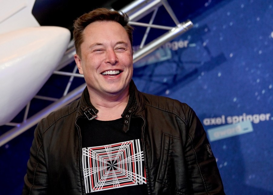 Elon Musk in front of a blue and white background.