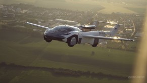 A car with wings flies high above the ground.