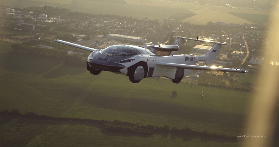 A car with wings flies high above the ground.