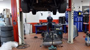 A car sits in a mechanic's shop with its engine removed