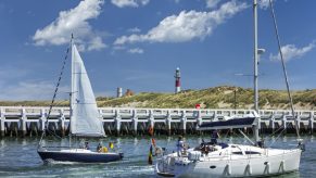 Sailboats and yachts sailing past wooden docks.