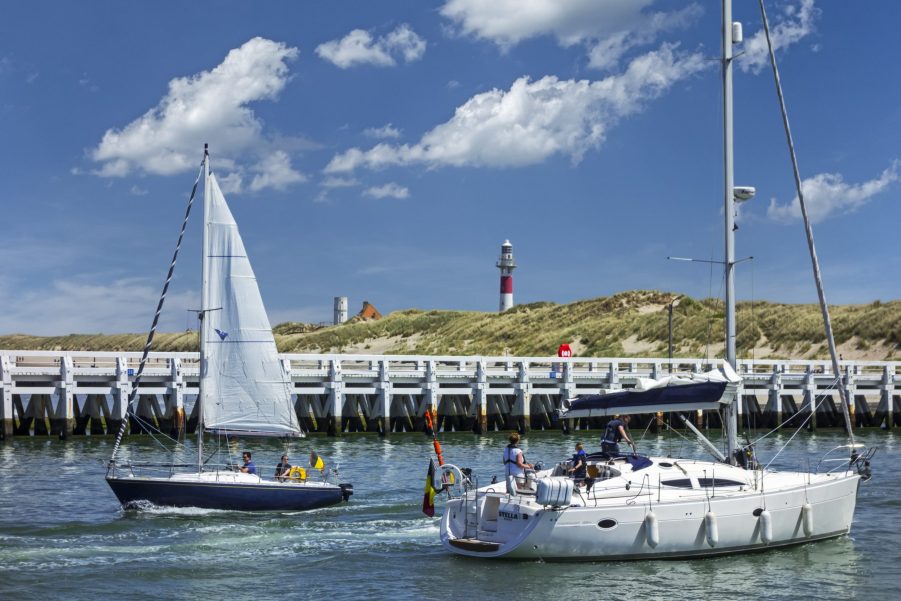 Sailboats and yachts sailing past wooden docks.