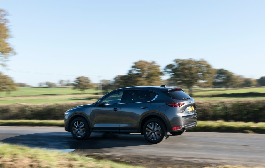 The second generation Mazda CX-5 driving at speed on a scenic country road.