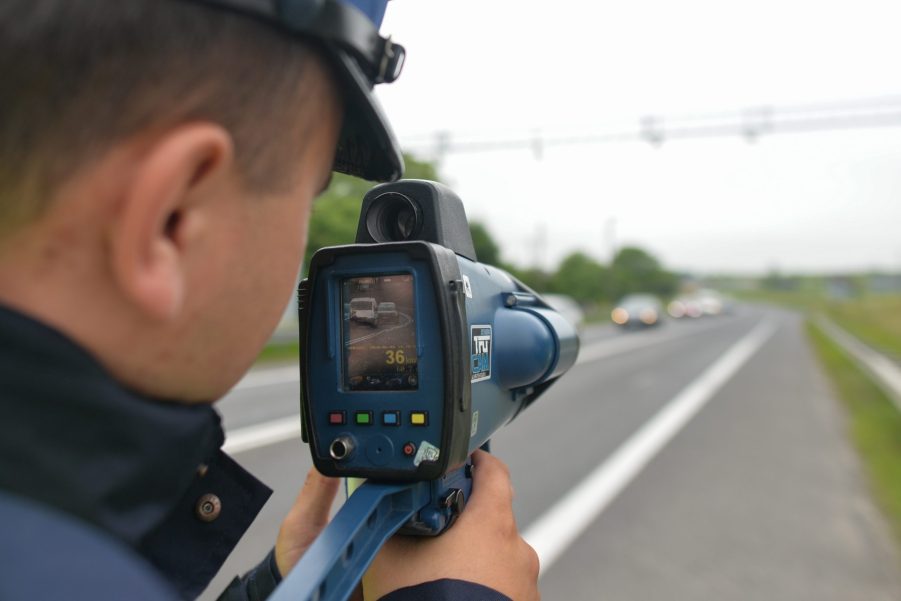 A police officer aims a radar gun at traffic looking for speeders