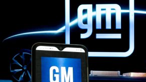 The old and new GM logos illuminated against a black backdrop