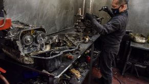 A mechanic works on a replaced engine on a workbench in a garage