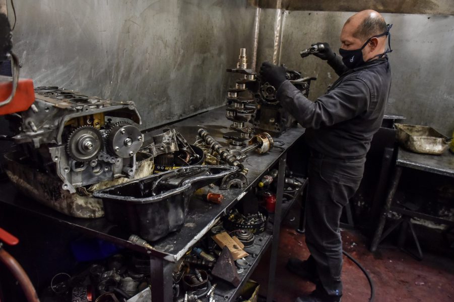 A mechanic works on a replaced engine on a workbench in a garage