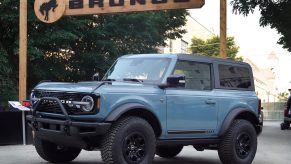 A grey Ford Bronco sits under a sign bearing its name at a press launch