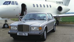 A Bentley Turbo R sits beside a private jet on a runway