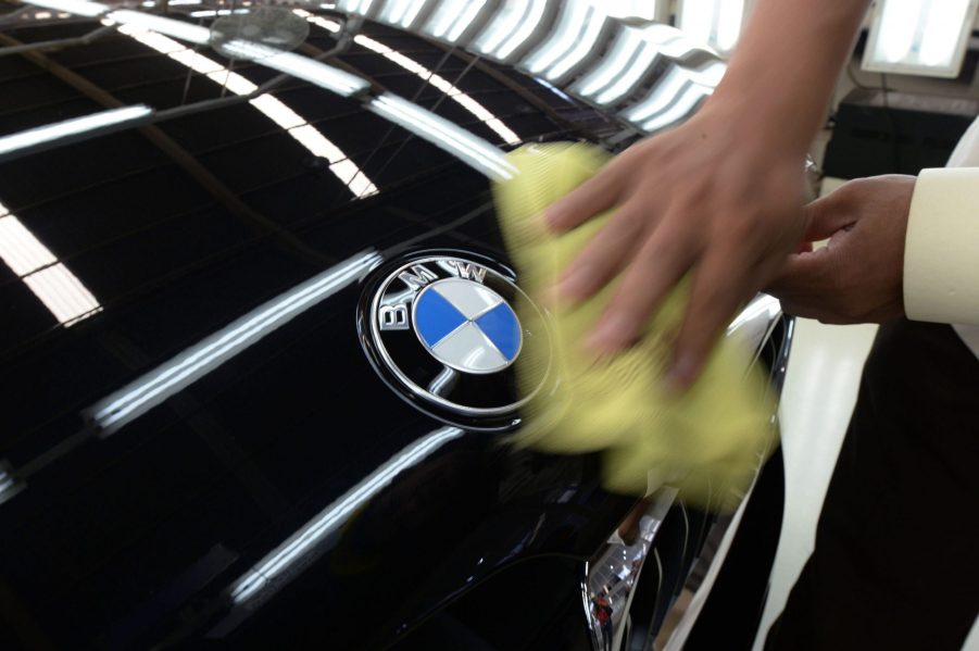 A man polishes the hood of a black BMW