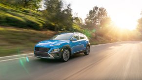 A blue Hyundai Kona driving, the Hyundai Kona is a cheap new car that offers an affordable base model