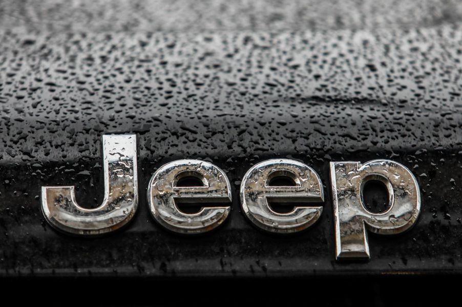 Jeep's logo in silver on a black car with raindrops