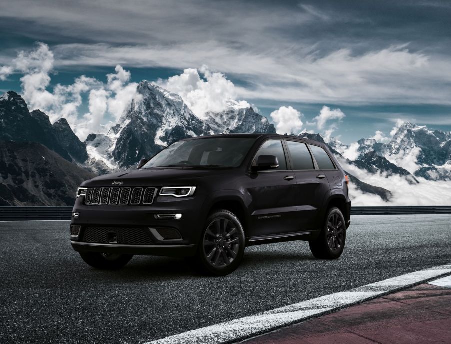 A black Jeep Grand Cherokee model parked on a racetrack near snowy and cloudy mountains