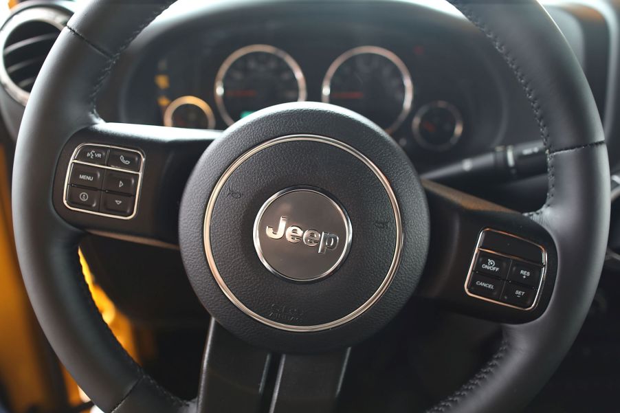 A black Jeep steering wheel with the name printed in the center. The background is the gauge cluster.