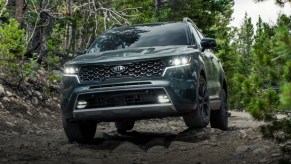 A dark 2021 green Kia Sorento drives through the woods.