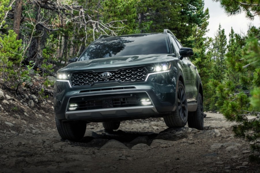 A dark 2021 green Kia Sorento drives through the woods.