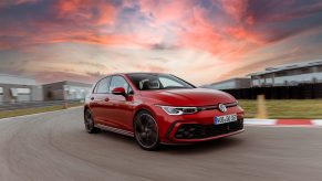 A red 2022 Volkswagen GTI on a racetrack at sunset in Germany