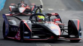 Nissan's black Formula E Racer coated in sponsor advertisements and logos driving around the track.