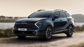 A dark colored 2023 Kia Sportage parked in sand