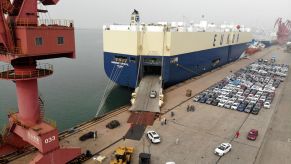 Cars driving into a large shipping container for overseas transportation