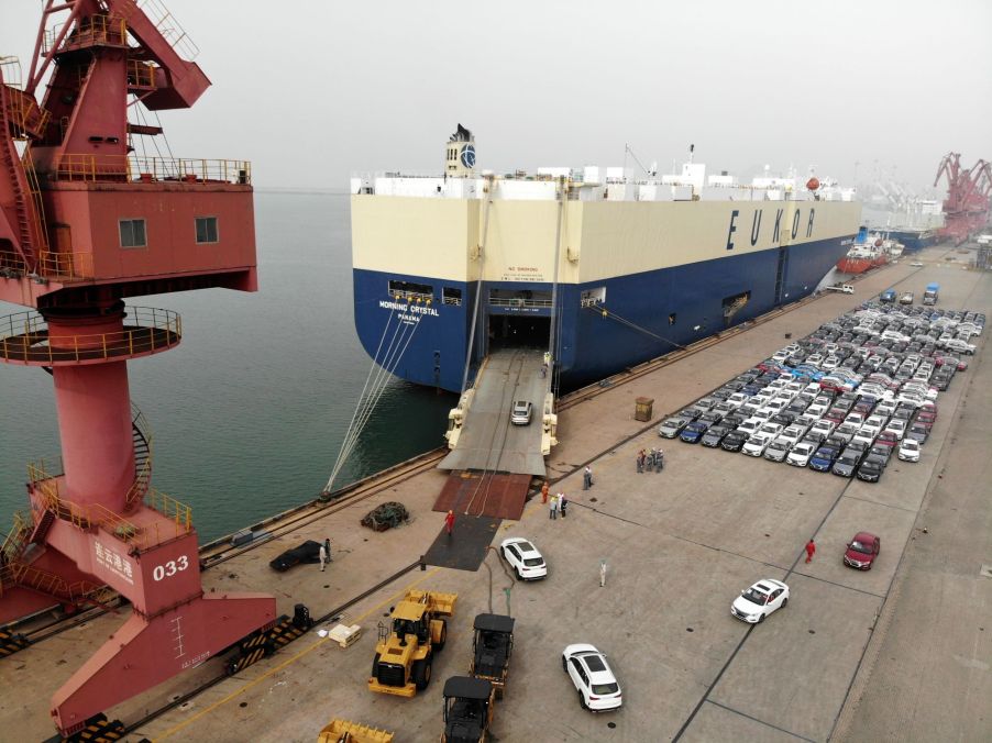 Cars driving into a large shipping container for overseas transportation