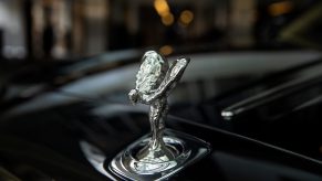 A silver Spirit of Ecstasy hood ornament on a black Rolls-Royce