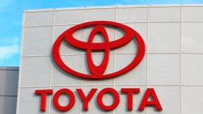 Closeup of Toyota's logo in red on the front of a ivory building with 'Toyota' written underneath it.