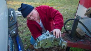 A man fixing a tow hitch to a horse trailer