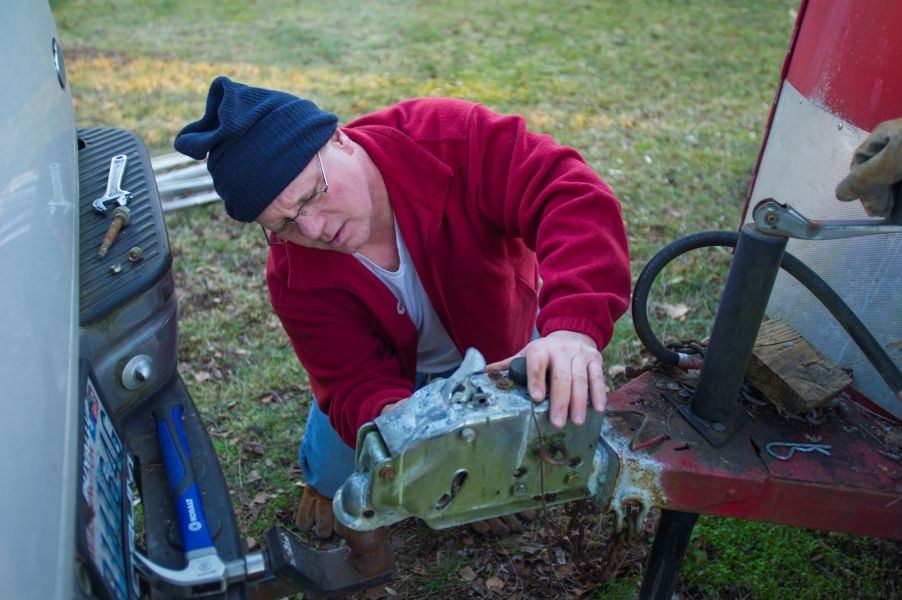 A man fixing a tow hitch to a horse trailer