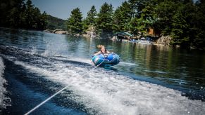 A woman on a tube being pulled across a lake by a speedboat