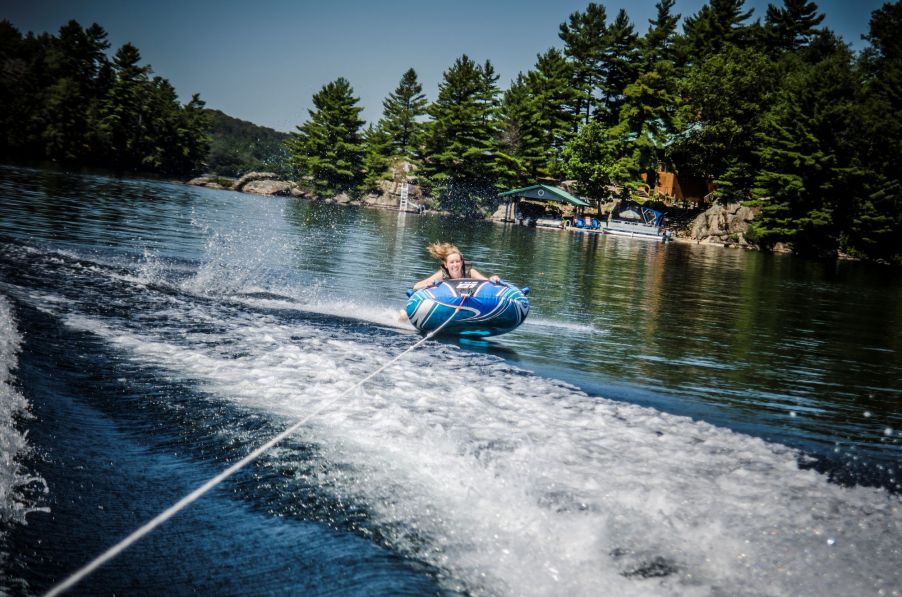 A woman on a tube being pulled across a lake by a speedboat