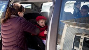 Hannah DeWick, 15, straps her newly adopted sister, Paisley, 2, into her car seat in a minivan in Rockport, Maine