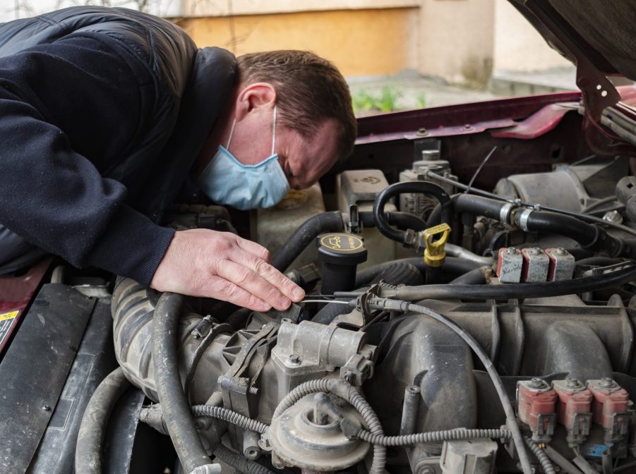 A mechanic wearing checks a car engin