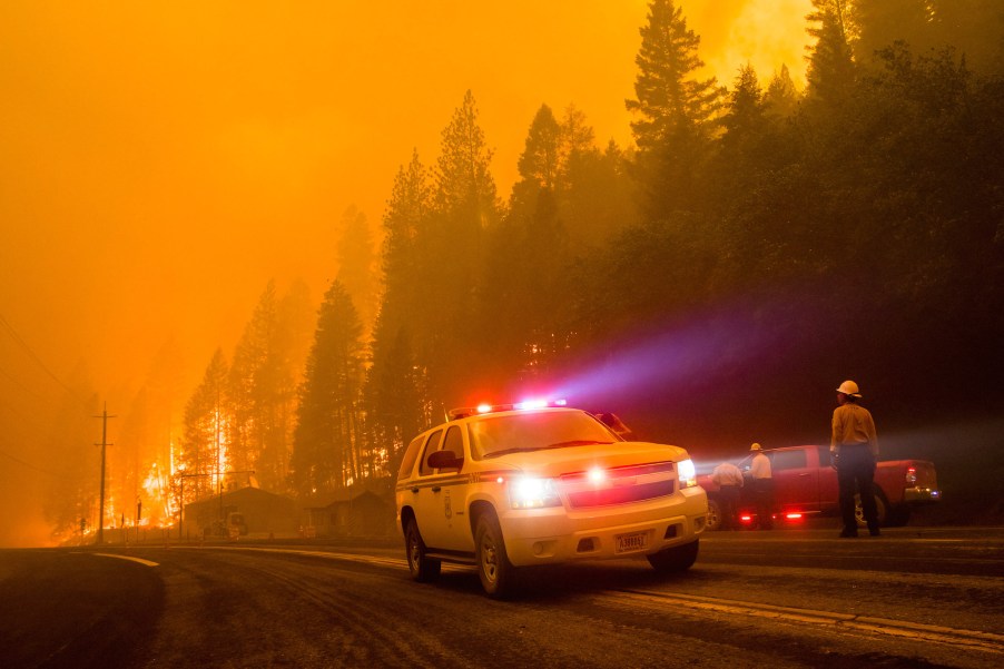 Firefighters block the road as a forest fire reaches a highway in California