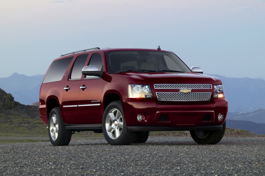 A burgendy 2011 Chevrolet Suburban LTZ full-size SUV parked on gravel in front of misty mountains