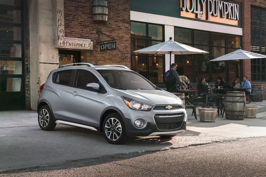 A silver 2021 Chevy Spark three-door hatchback parked outside a Jolly Pumpkin bakery and café