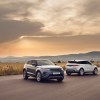 Two 2021 Land Rover Range Rover Evoque luxury compact SUVs parked on a road through a plain in front of mountains