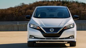 A white Nissan Leaf EV on a shoulder, sitting in the sun