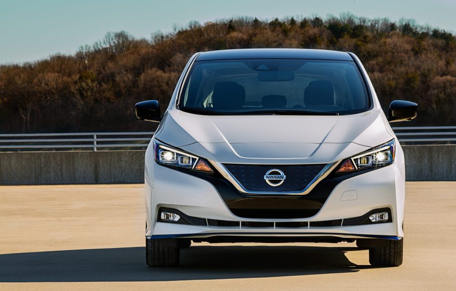 A white Nissan Leaf EV on a shoulder, sitting in the sun