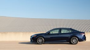 The 2021 Toyota Camry XLE sedan in dark blue parked near a concrete barrier