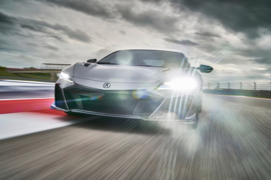 A silver 2022 Acura NSX Type S supercar travels on a racetrack under a cloudy sky