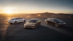 A white, gold, and brown 2022 Lucid Air parked next to a desert