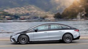 The 2022 Mercedes-Benz EQS electric sedan driving on a highway near docks