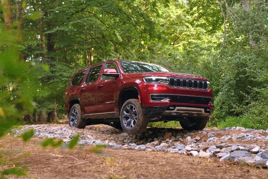 A red 2022 Wagoneer with Advanced All-Terrain Group off-roading through the forest