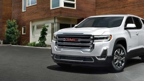 A white 2021 GMC Acadia in front of a brick house.