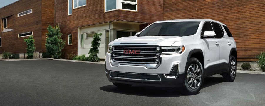 A white 2021 GMC Acadia in front of a brick house.