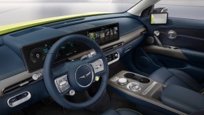 The dark-blue front seats and dashboard of a chartreuse 2023 Genesis GV60 electric crossover SUV