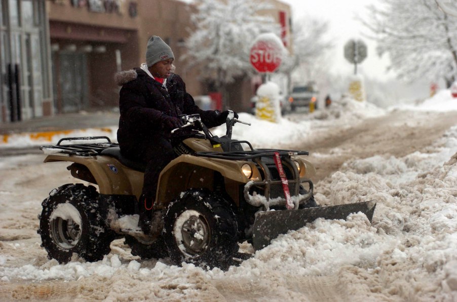 D'Rand Richardson uses a plow-fitted ATV to clear the parking lot in front of a Big Lots store in Louisville, Colorado